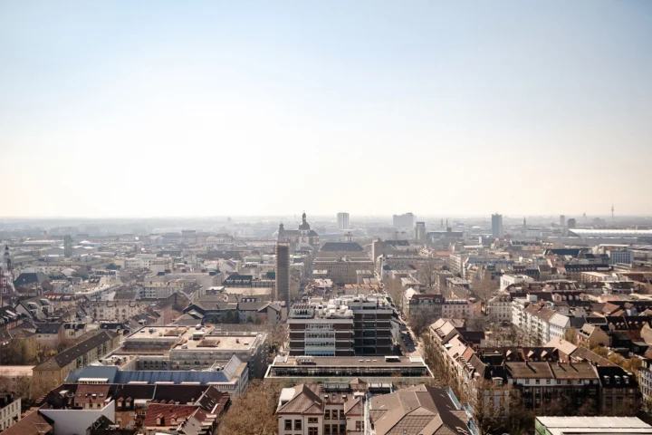 Aerial view of the city of Mannheim with numerous buildings under a clear sky.