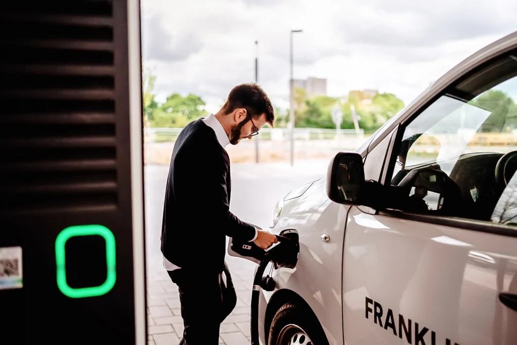 Eine Person lädt ein Elektrofahrzeug an einer Ladestation auf.