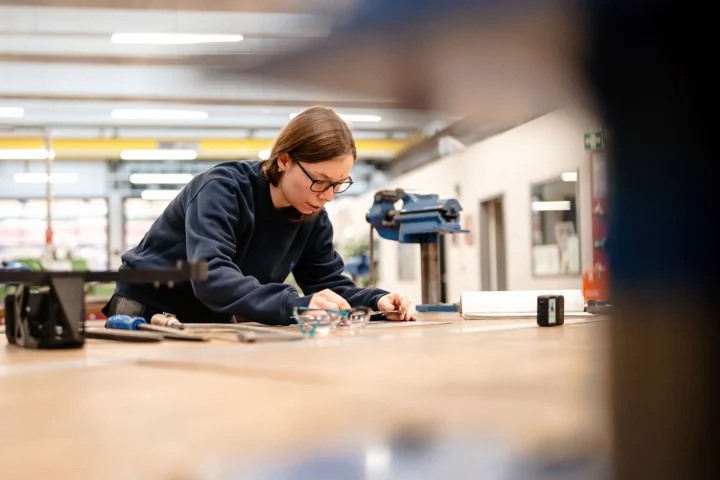 Eine Person arbeitet konzentriert an einem Werkstück in einer Werkstatt.