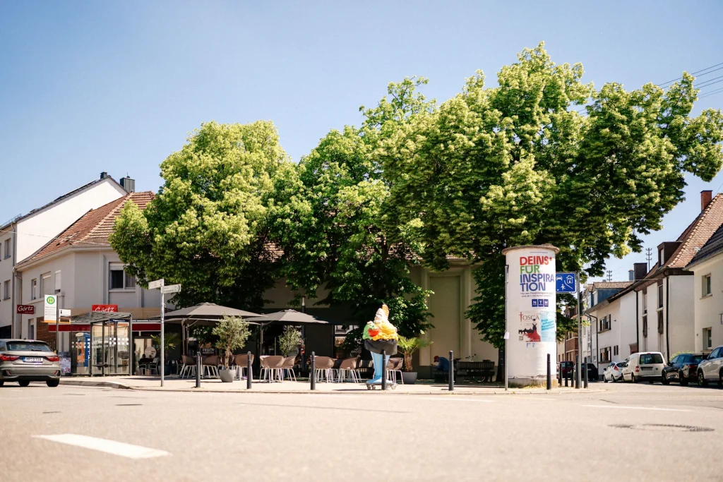 Straßenkreuzung mit Café, großem Baum und Eisdiele in Mannheim.