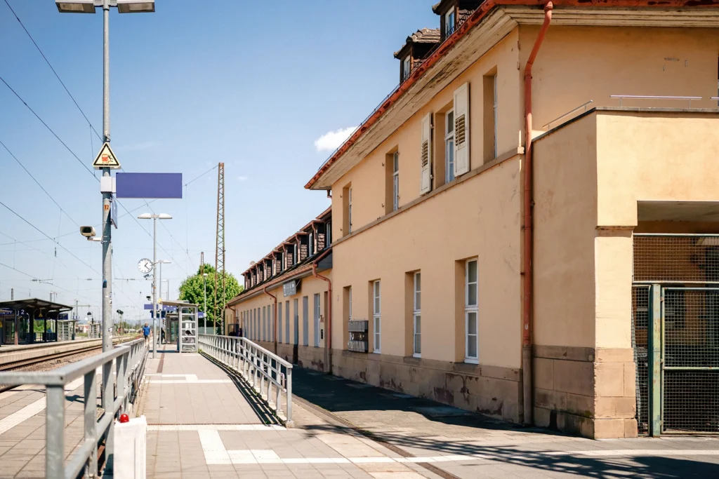 Ein Bahnhofsgebäude mit Bahnsteigen, Gleisen und einem barrierefreien Zugang erstreckt sich entlang der Schienen.