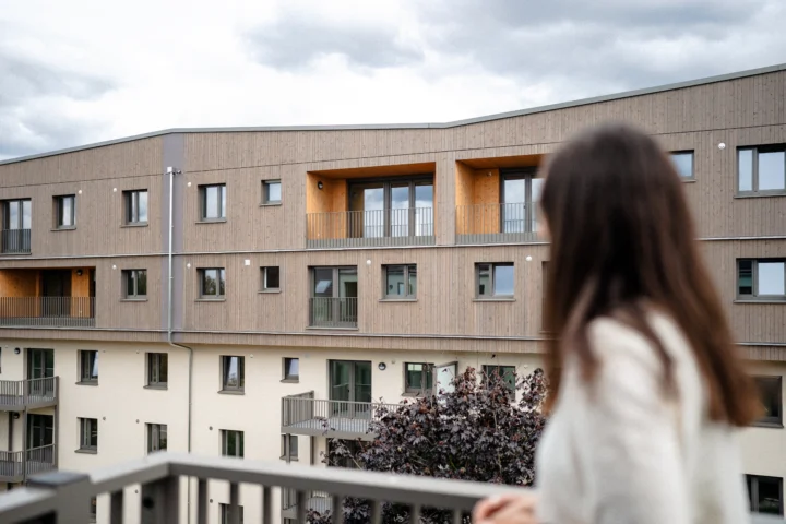 Blick auf modernisierte Wohngebäude im Patrick-Henry-Village, im Vordergrund unscharf eine Frau von hinten am Geländer.