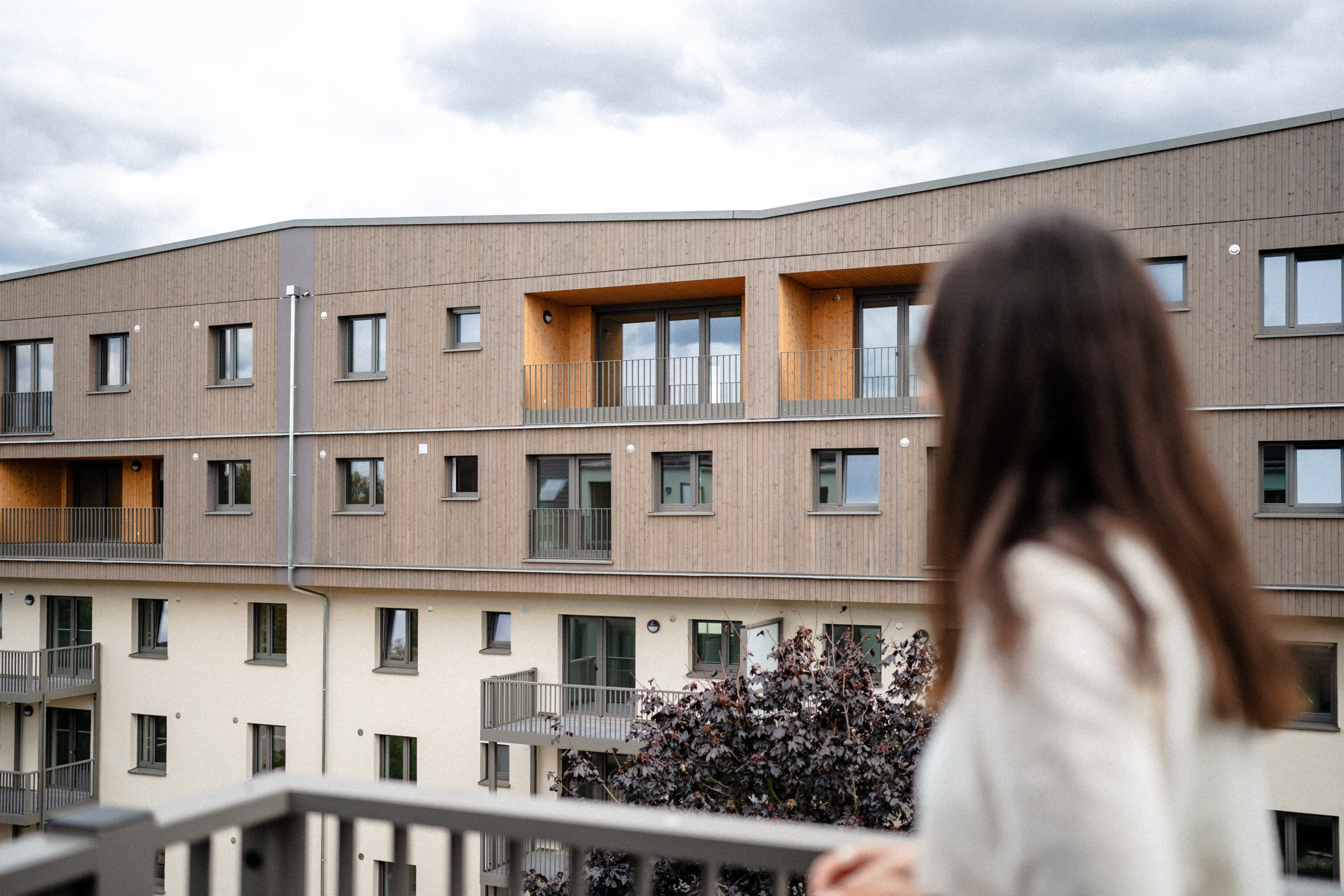 Blick auf modernisierte Wohngebäude im Patrick-Henry-Village, im Vordergrund unscharf eine Frau von hinten am Geländer.