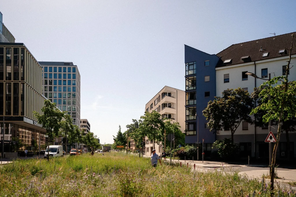 Modernes Stadtquartier mit Wohn- und Bürogebäuden sowie einer begrünten Freifläche.