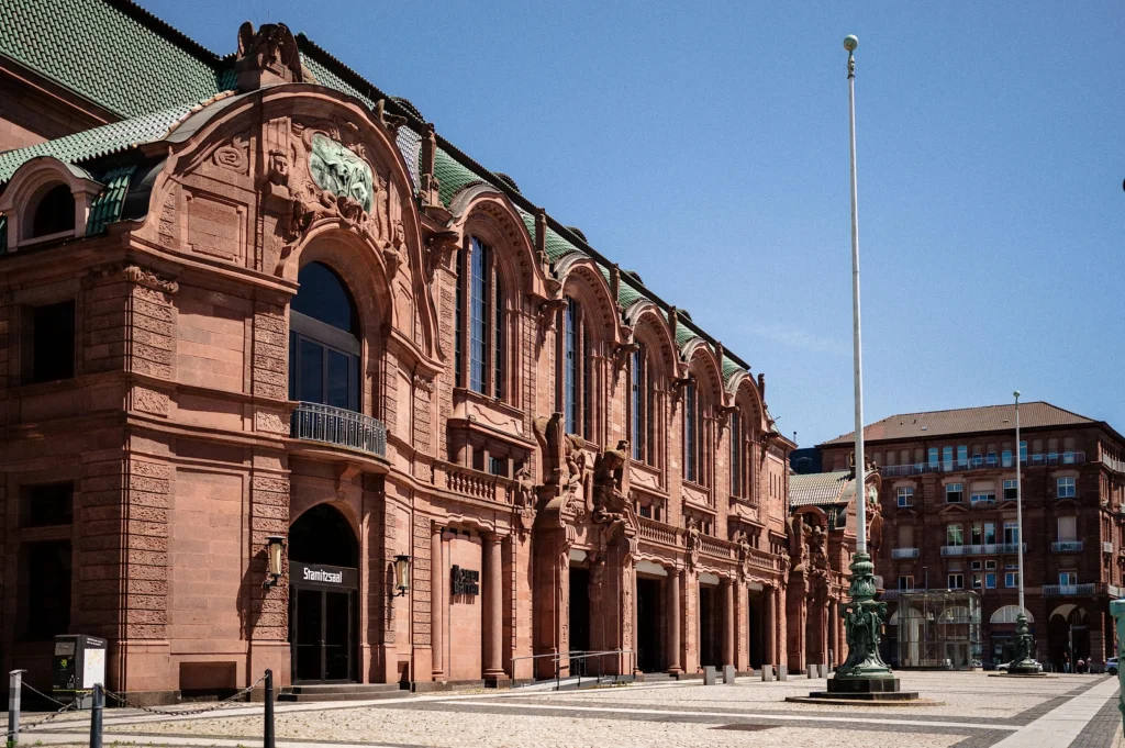 The richly decorated sandstone façade of the Rosengarten dominates a spacious square with historic lamp posts and surrounding buildings.
