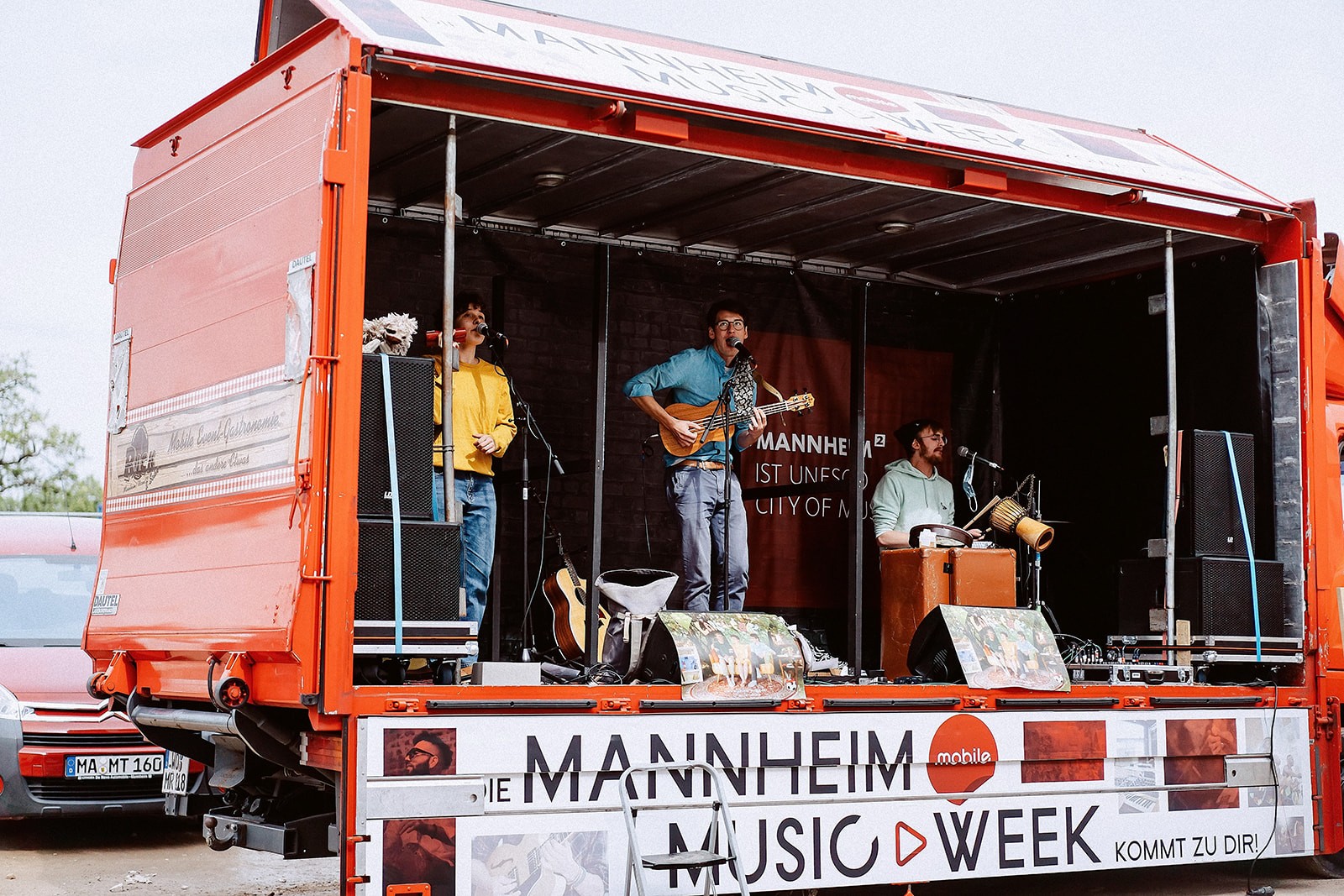 Ein Bild, auf dem die Crew der Music Week Mannheim leidenschaftlich Musik macht. Die Musiker stehen auf der mobilen Bühne und spielen ihre Instrumente mit vollem Einsatz.
