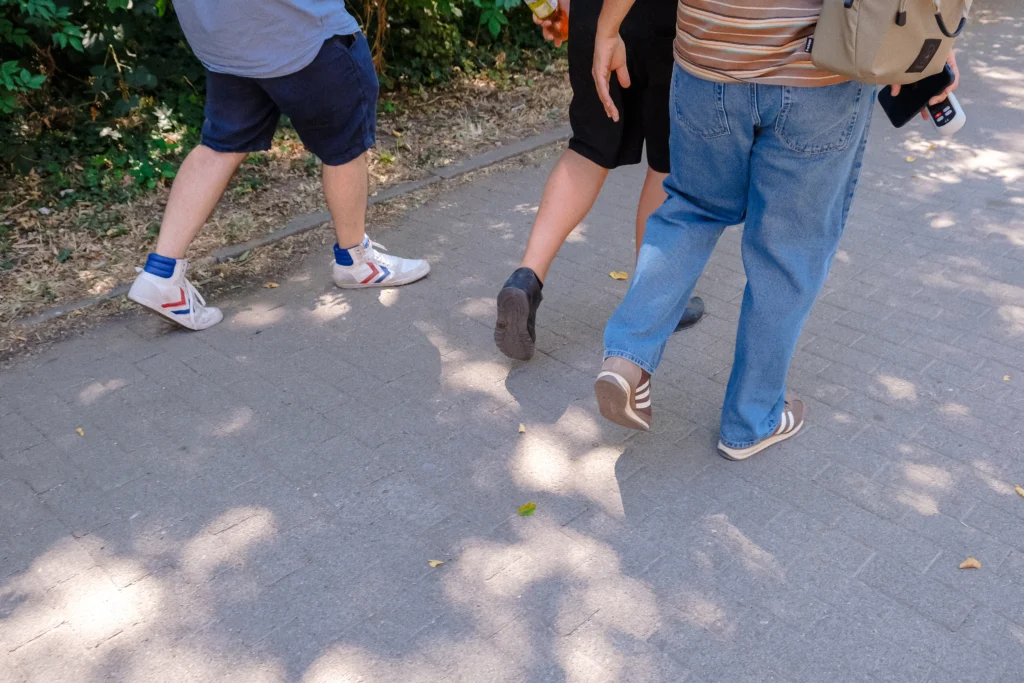 Detailaufnahme von Personen, die gemeinsam auf einem Gehweg durch das Quartier laufen.