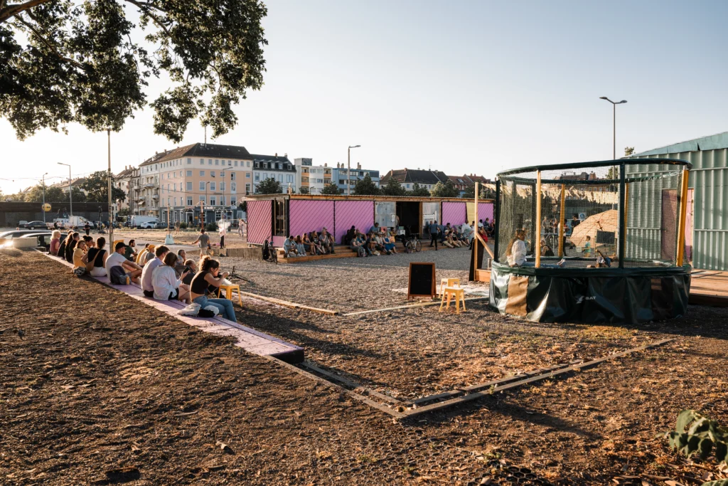 Menschen sitzen bei Sonnenschein im Außenbereich des ALTER in Mannheim.