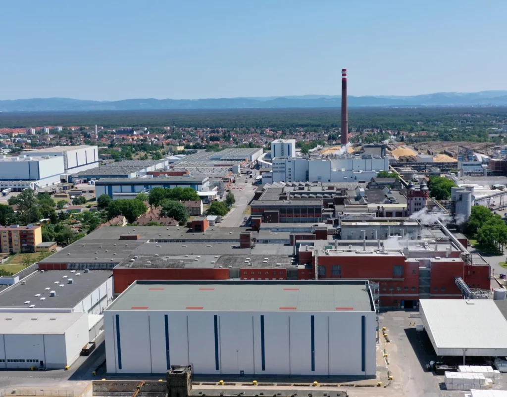 Luftaufnahme des Essity Firmengeländes mit mehreren großen Industriegebäuden und einem hohen Schornstein im Hintergrund.