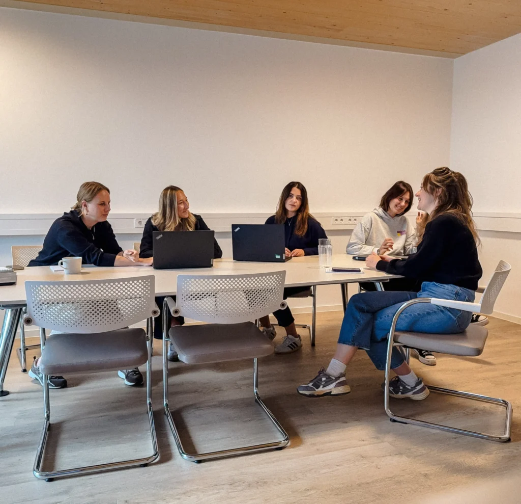 Eine Gruppe Frauen sitzt an einem Tisch in einem Besprechungsraum.