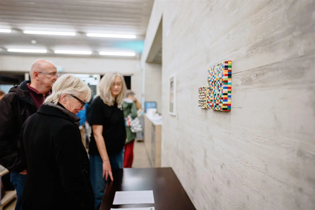 Besucherinnen und Besucher betrachten Kunstwerke in einer Galerie.